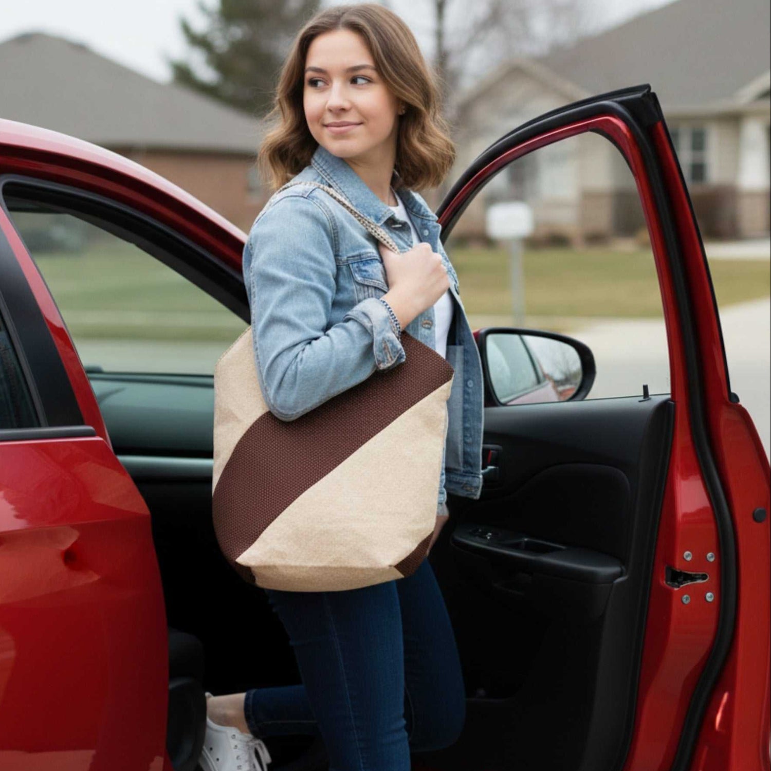 Woman getting out of a red car, carrying the Chocolate Brown Minimalist Tote Bag Diagonal Stripe Tote Bag on her shoulder. The bag's sturdy shape and size are visible as she exits the vehicle.