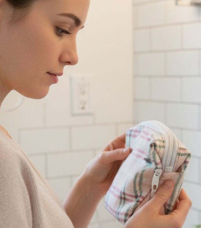 Woman holding an x small pink Flannel Plaid Zipper Pouch makeup pouch ln a bathroom setting
